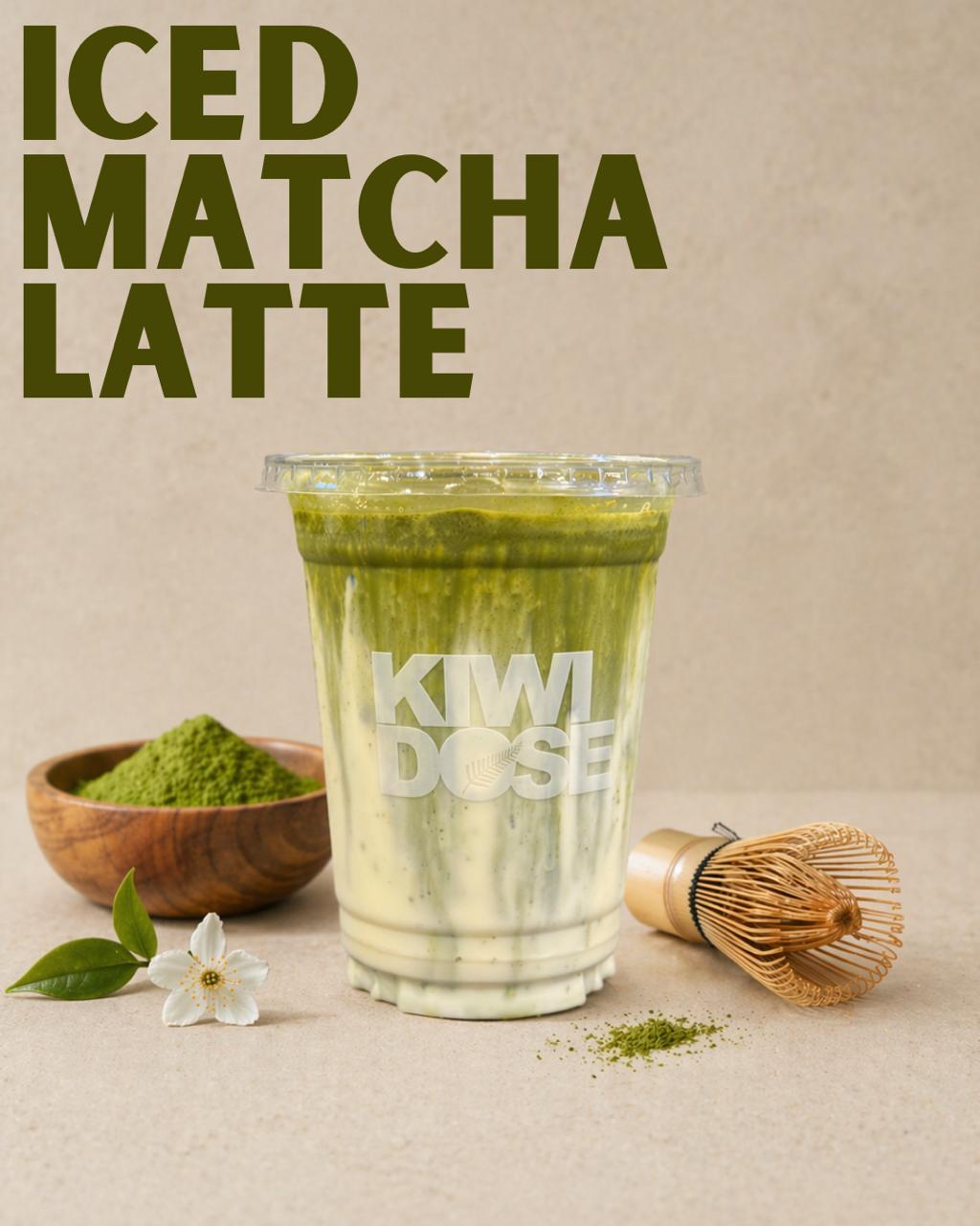 Iced matcha latte beside a bowl of matcha powder and a bamboo whisk